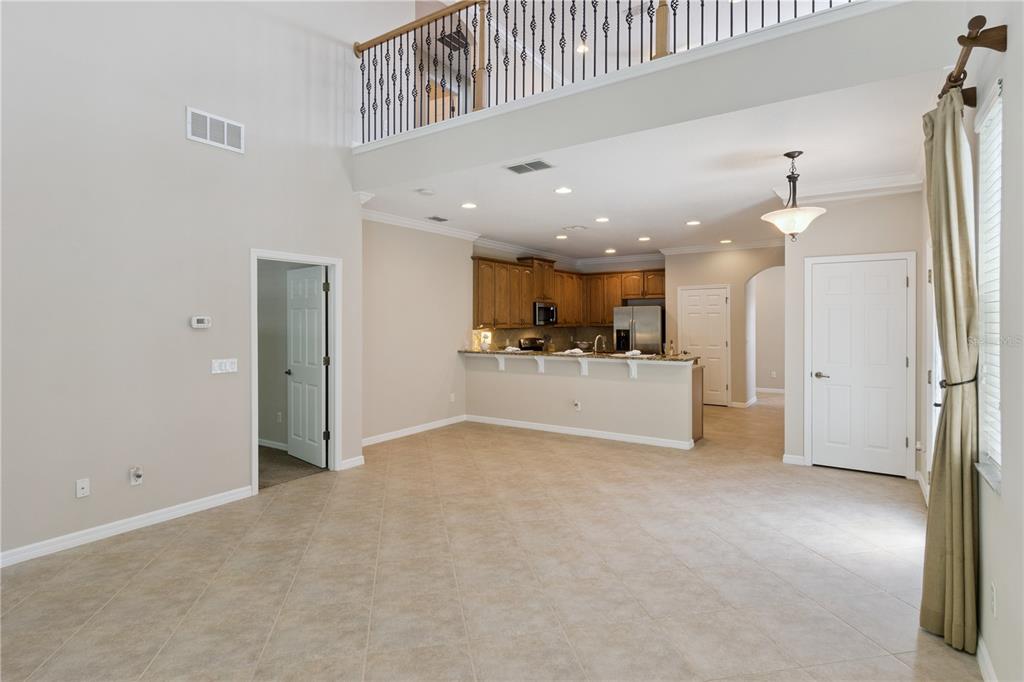 An open-concept living area features tile flooring, a kitchen with wood cabinets, and a lofted balcony — 624 VENICE PLACE, SANFORD, FL