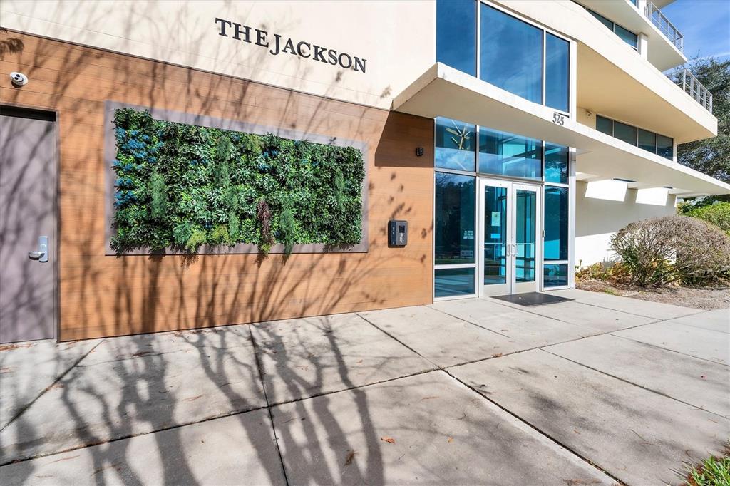 The exterior of a modern building entrance features wood-paneled walls, a vertical garden, and glass doors — 525 E JACKSON STREET UNIT 305, ORLANDO, FL