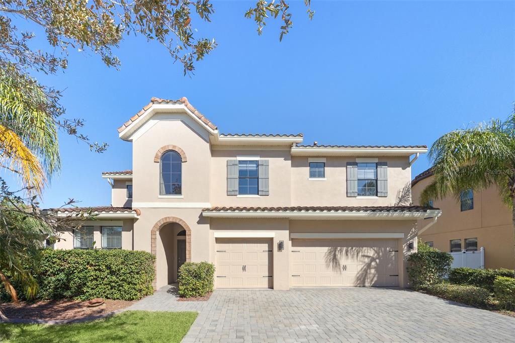 A two-story stucco house with a three-car garage and a paved driveway under a blue sky — 1501 PRAIRIE OAKS DRIVE, ST CLOUD, FL