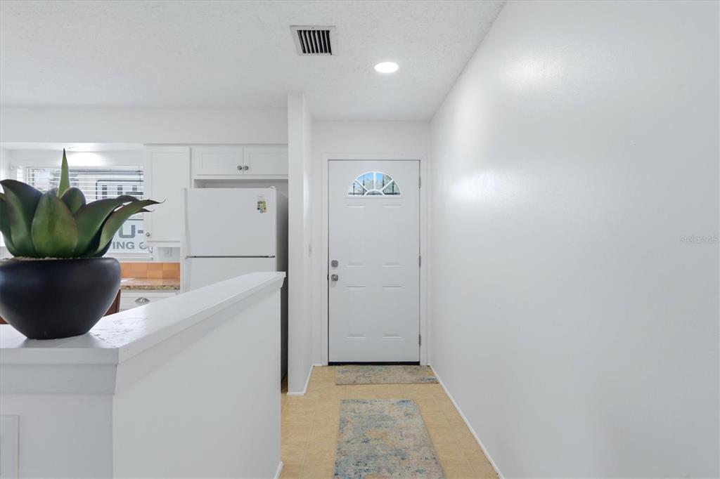 A white front door opens into a small entryway with tile flooring and a kitchen — 4538 PAWNEE TRAIL UNIT 197, SARASOTA, FL