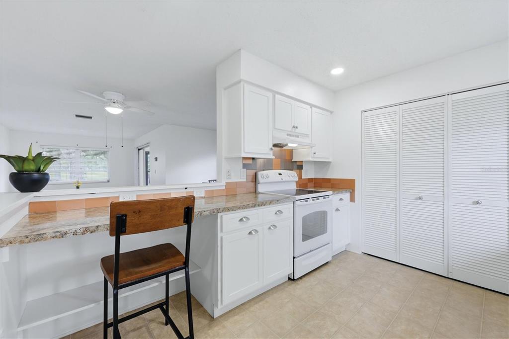 A kitchen features white cabinets, granite countertops, a white stove, and a breakfast bar — 4538 PAWNEE TRAIL UNIT 197, SARASOTA, FL