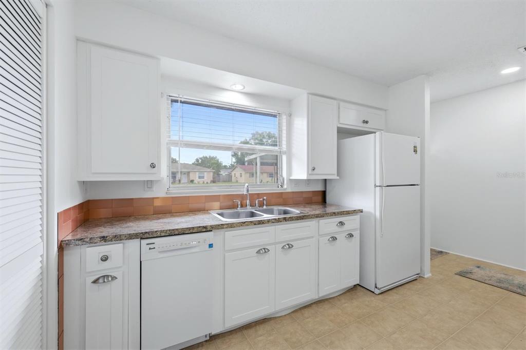 A kitchen with white cabinets, a granite countertop, a double sink, and a white refrigerator — 4538 PAWNEE TRAIL UNIT 197, SARASOTA, FL