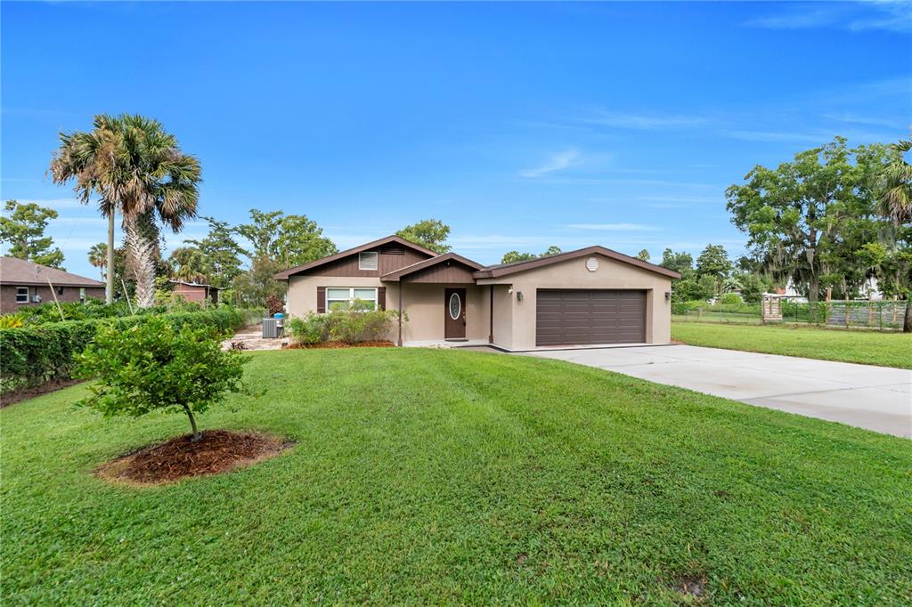 A single-story house with a tan exterior, brown garage door, and a large front lawn — 9431 LAKE MARION CREEK ROAD, HAINES CITY, FL