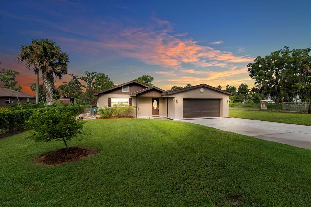 A single-story house with a brown garage and front door sits on a grassy lawn — 9431 LAKE MARION CREEK ROAD, HAINES CITY, FL