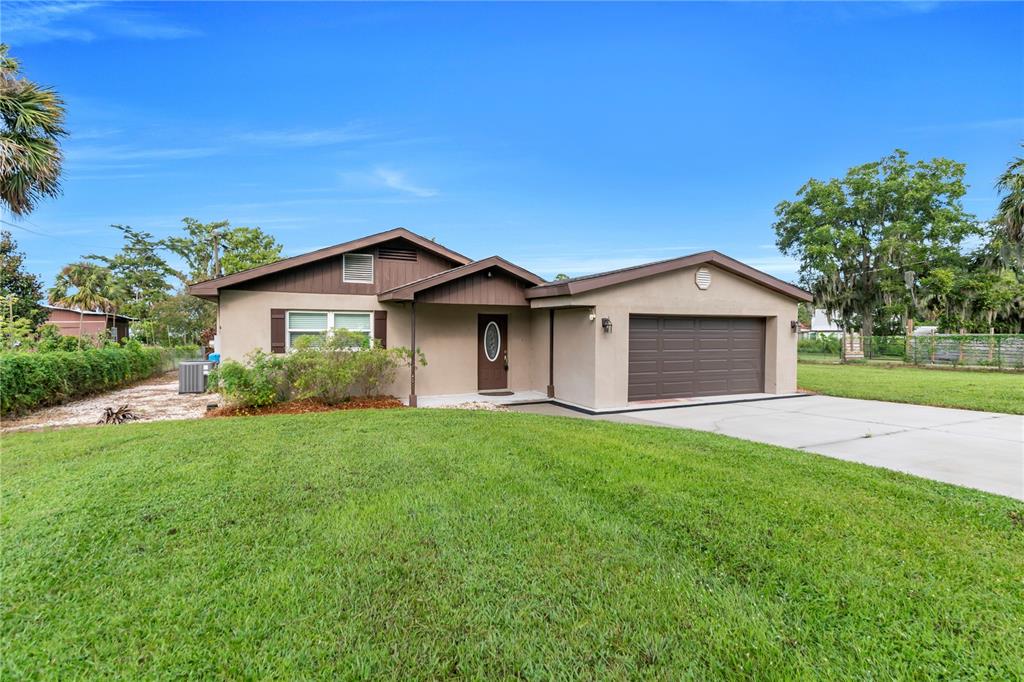 A single-story house with a brown garage door, tan stucco exterior, and a front lawn — 9431 LAKE MARION CREEK ROAD, HAINES CITY, FL