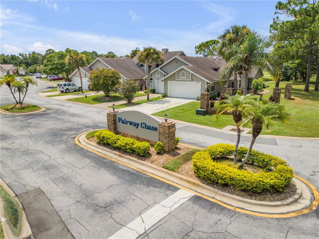 A street-level view of a residential neighborhood entrance sign labeled Fairway Chase — 2016 CORNELL PLACE, PORT ORANGE, FL