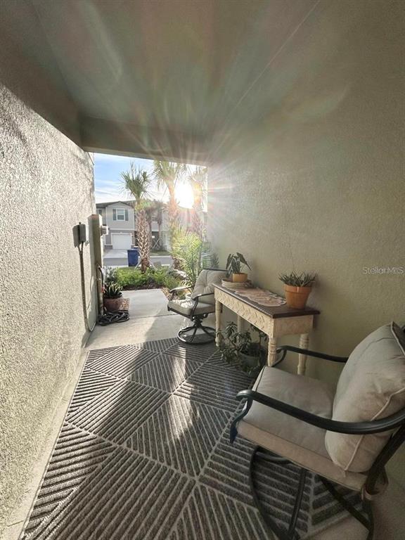 A covered patio features a patterned rug, two chairs, and a console table — 6199 SHINER STREET, LAND O LAKES, FL