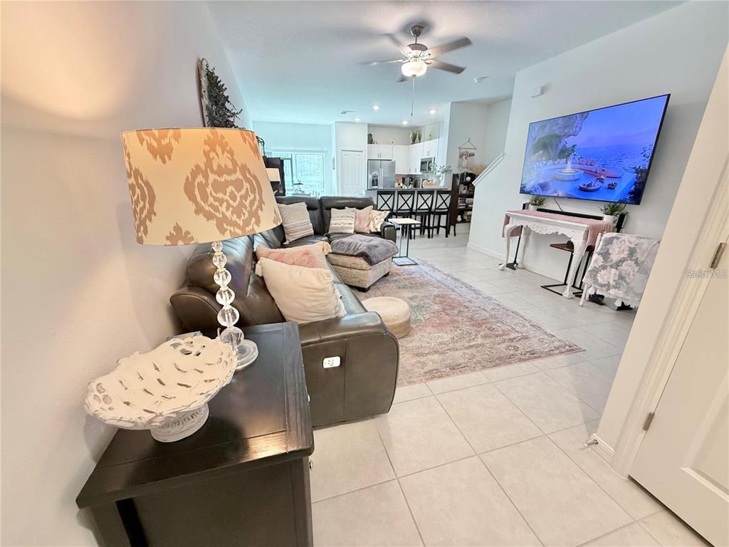 A living room features a gray sectional sofa, a patterned rug, and a wall-mounted television — 6199 SHINER STREET, LAND O LAKES, FL