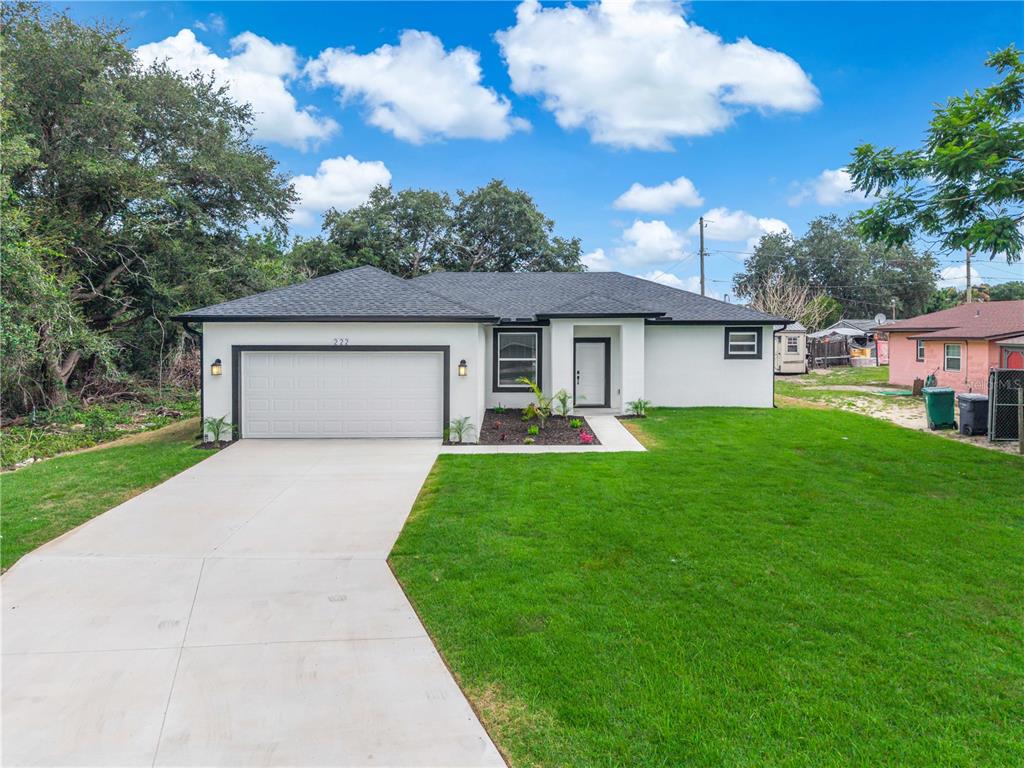 A single-story house with a white exterior, black trim, and a concrete driveway — 222 FLORIDA AVENUE, DUNDEE, FL
