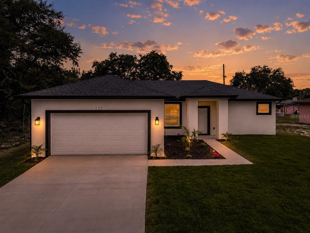 A single-story house with a white stucco exterior, dark roof, and an attached garage — 222 FLORIDA AVENUE, DUNDEE, FL