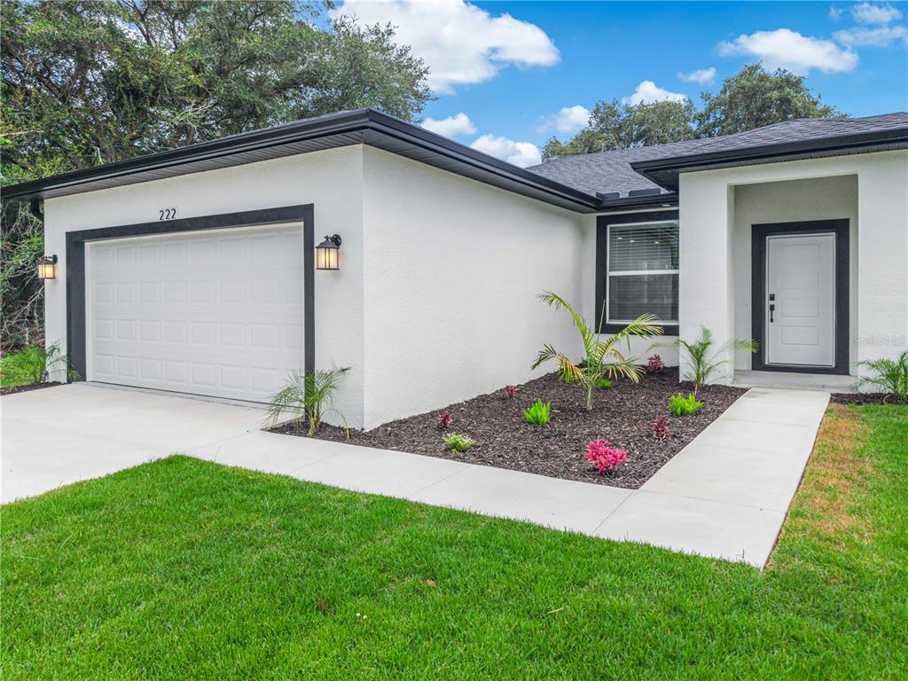 A white detached garage with a black trim and a concrete driveway under a blue sky — 222 FLORIDA AVENUE, DUNDEE, FL