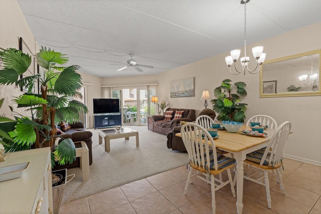 An open-concept living and dining area features carpeted floors, a ceiling fan, and sliding doors — 5650 S A1A UNIT UNIT G117, ST AUGUSTINE, FL
