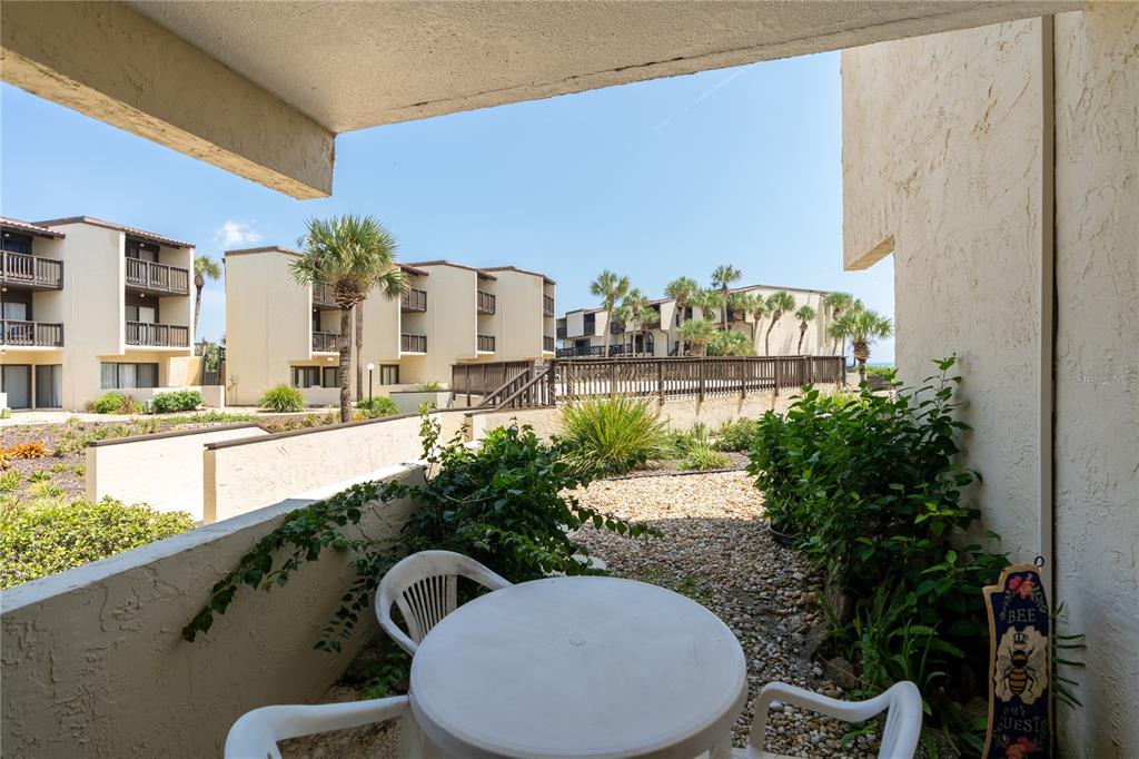 A ground-level patio with a white table and chairs overlooks a landscaped courtyard and buildings — 5650 S A1A UNIT UNIT G117, ST AUGUSTINE, FL