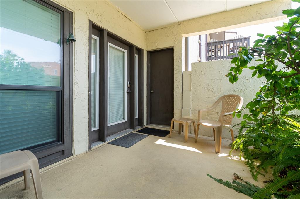 A covered patio features a beige concrete floor, a tan plastic chair, and a small door — 5650 S A1A UNIT UNIT G117, ST AUGUSTINE, FL