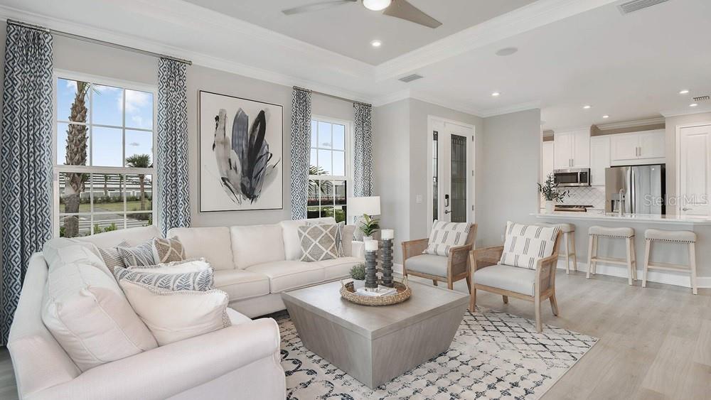 A bright living room with a white sofa, coffee table, and an open-concept kitchen — 7452 MOONBEAM AVENUE, SARASOTA, FL