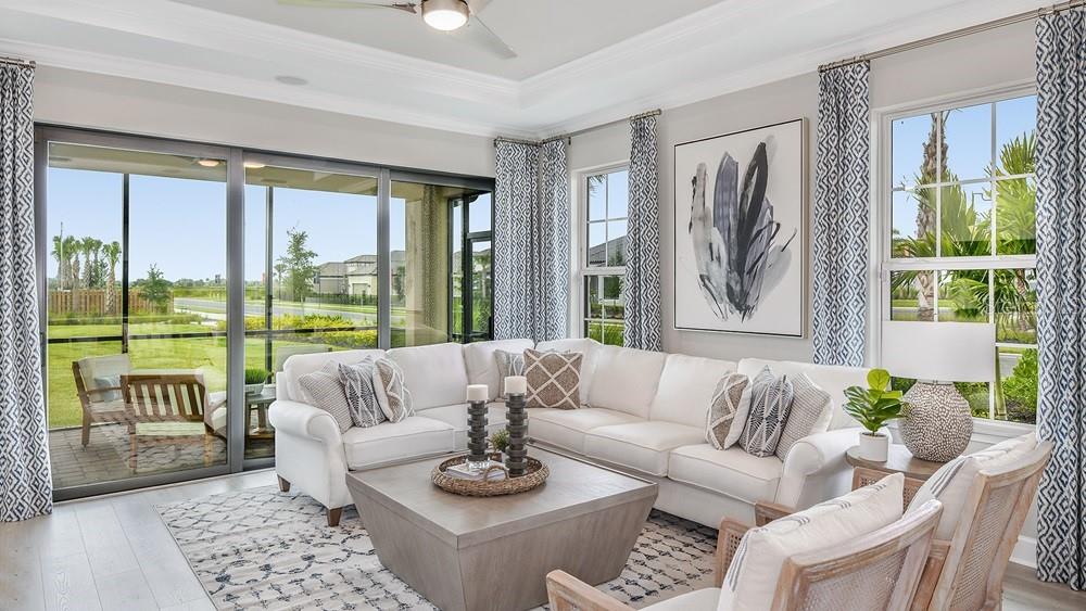 A bright living room features a white sectional sofa, a square coffee table, and large windows — 7452 MOONBEAM AVENUE, SARASOTA, FL