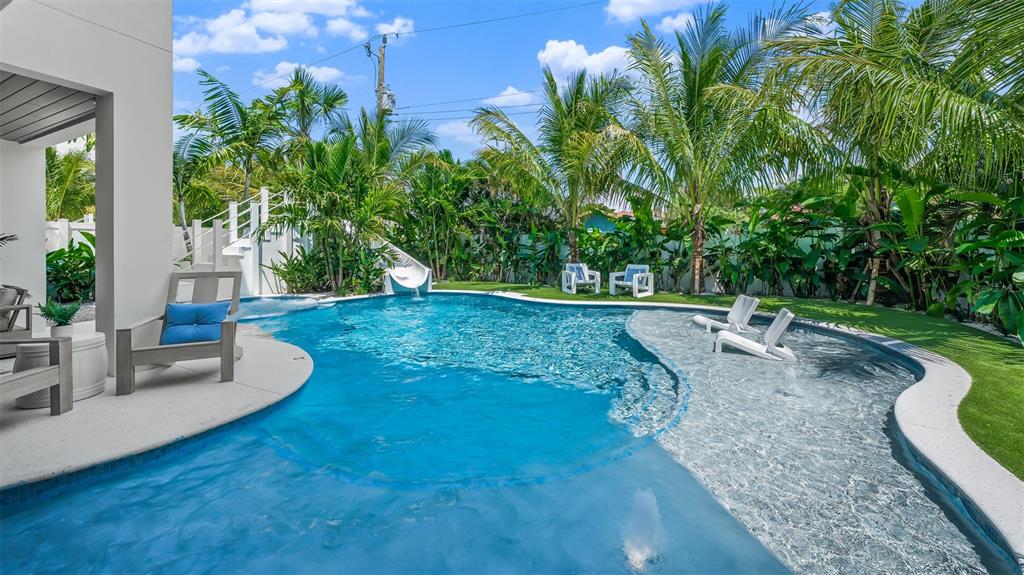 A backyard swimming pool features a slide, a sun shelf with lounge chairs, and landscaping — 161 TYLER DRIVE, SARASOTA, FL