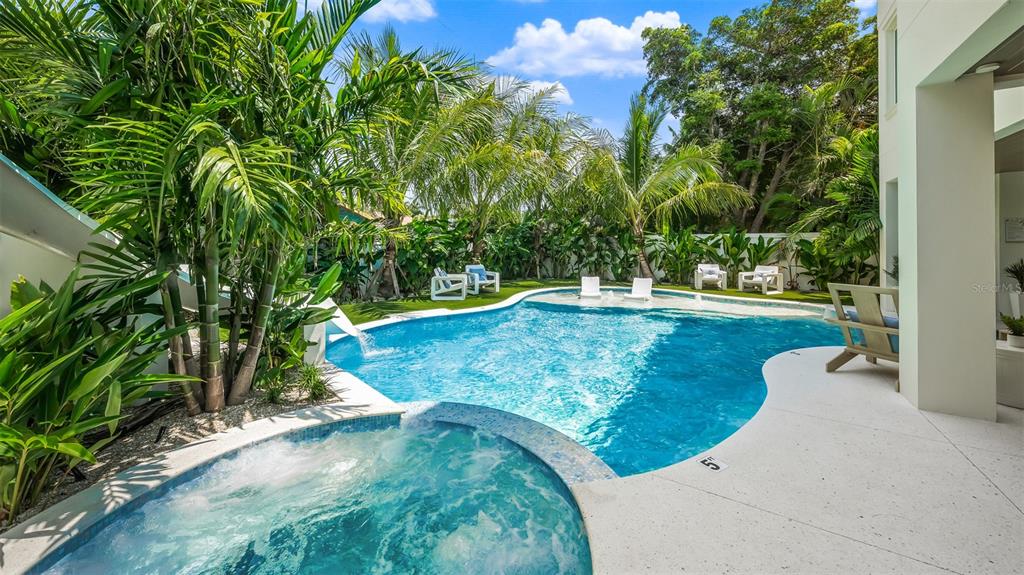 A swimming pool and hot tub sit on a patio surrounded by palm trees — 161 TYLER DRIVE, SARASOTA, FL