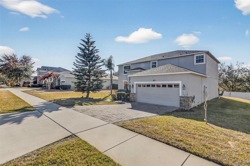 A two-story suburban house features a paved driveway, a two-car garage, and a large pine tree — 1336 LATTIMORE DRIVE, CLERMONT, FL