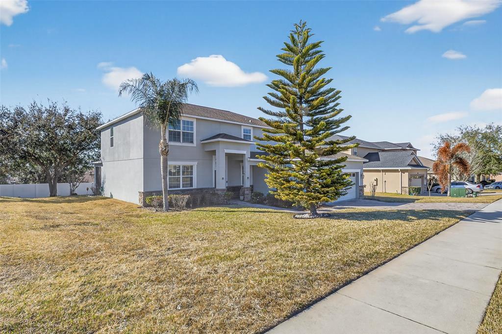A two-story suburban house with a large evergreen tree and a palm tree in front — 1336 LATTIMORE DRIVE, CLERMONT, FL
