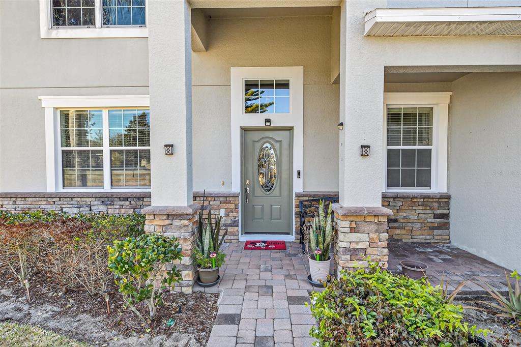 The exterior of a house features a stone-accented facade, a covered entryway, and a front door — 1336 LATTIMORE DRIVE, CLERMONT, FL