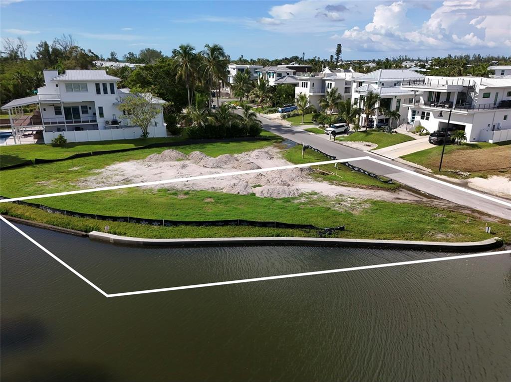 An aerial view of a vacant waterfront lot with a concrete seawall and surrounding houses — 6801 LONGBOAT DRIVE S, LONGBOAT KEY, FL