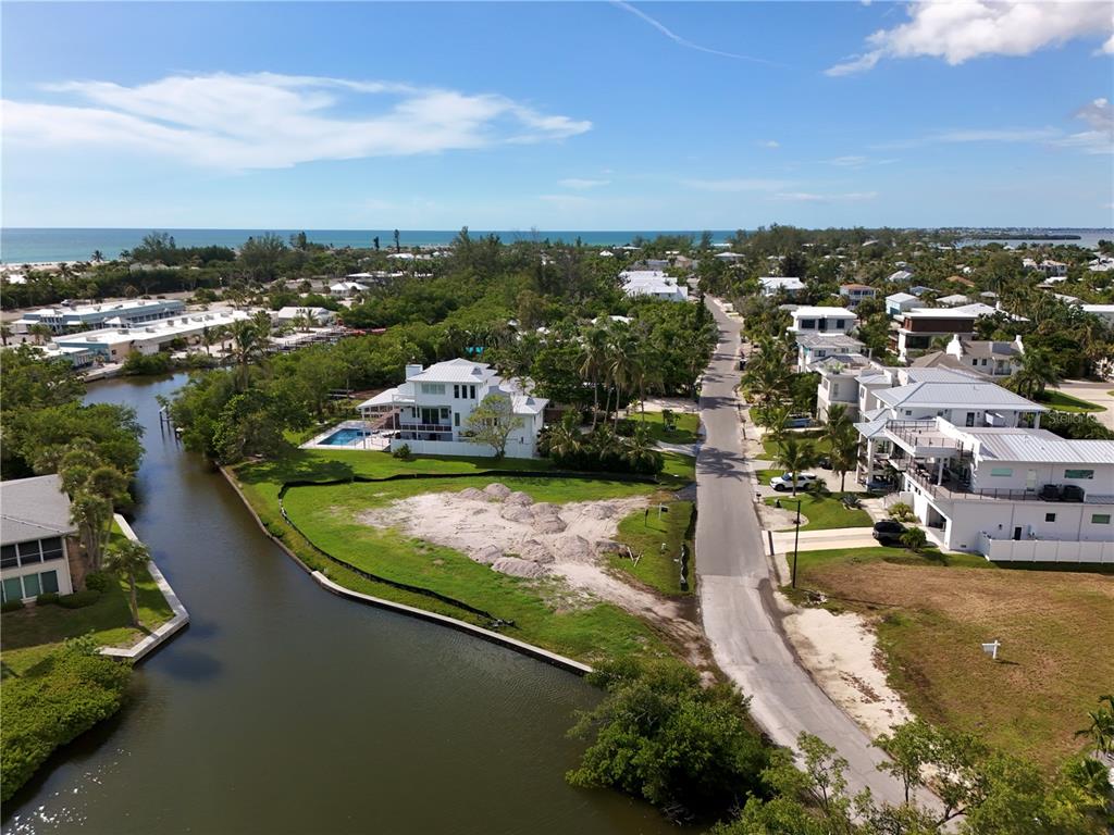 An aerial view shows a vacant waterfront lot next to a house with a pool — 6801 LONGBOAT DRIVE S, LONGBOAT KEY, FL