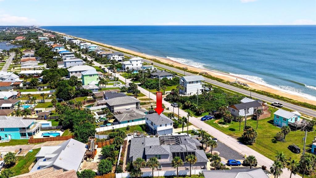 An aerial view shows a coastal neighborhood with a red arrow pointing to a house — 1901 N CENTRAL AVENUE, FLAGLER BEACH, FL