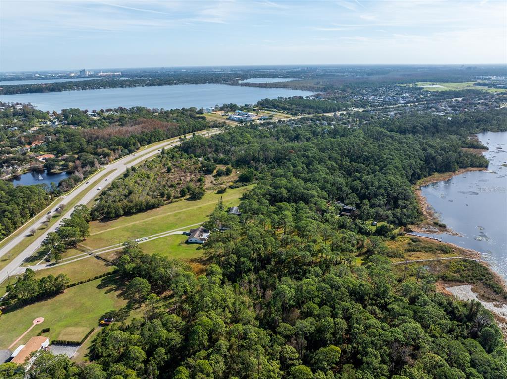 An aerial view shows a house situated between a highway and a lake — 8822 WINTER GARDEN VINELAND ROAD, ORLANDO, FL