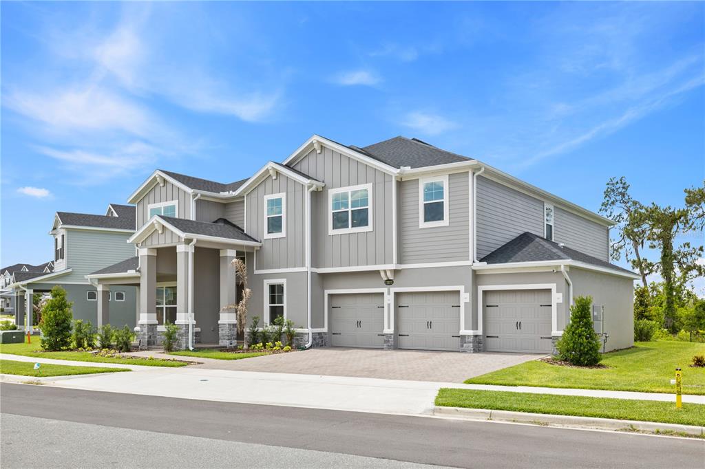 A two-story gray house with a three-car garage and a covered front porch — 17372 GLOSSY POMELO WAY, WINTER GARDEN, FL