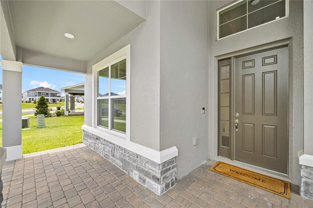 A covered front porch with stone veneer siding leads to a gray front door — 17372 GLOSSY POMELO WAY, WINTER GARDEN, FL