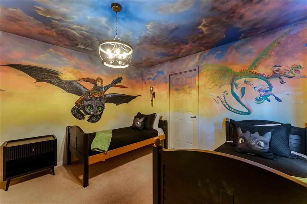 A bedroom features twin beds and walls painted with a How to Train Your Dragon mural — 2623 PAWNALL STREET, KISSIMMEE, FL