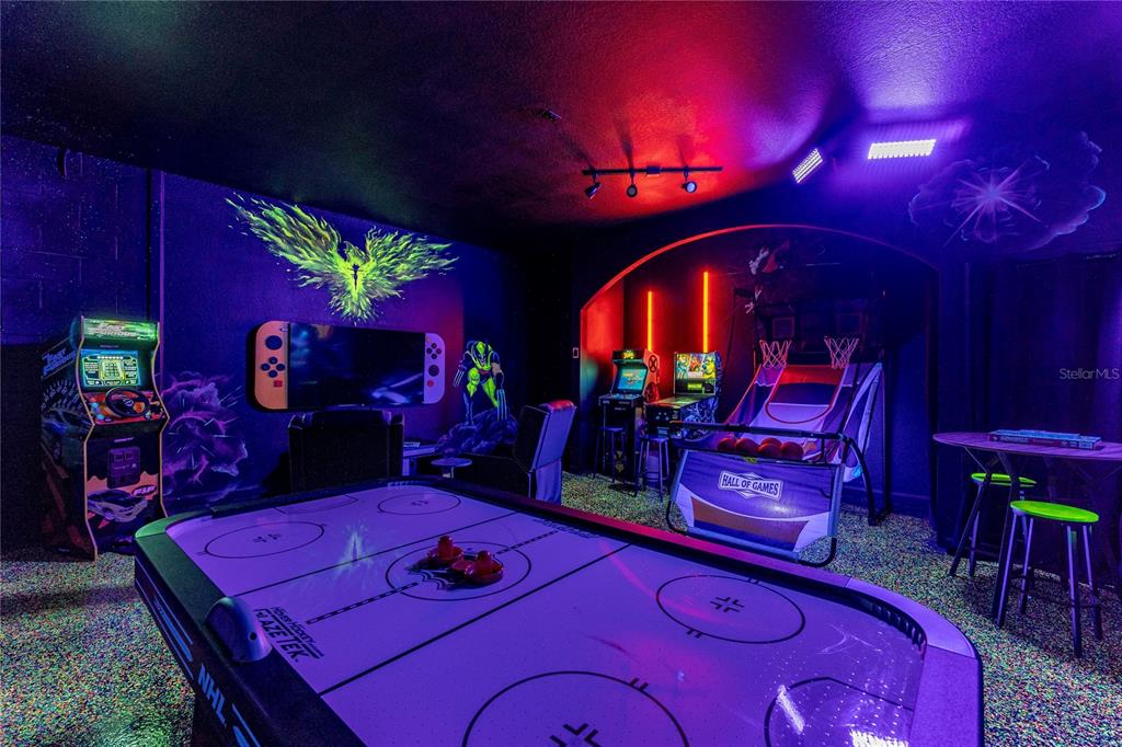 A game room features an air hockey table, arcade machines, a basketball game, and neon-style wall art — 2623 PAWNALL STREET, KISSIMMEE, FL