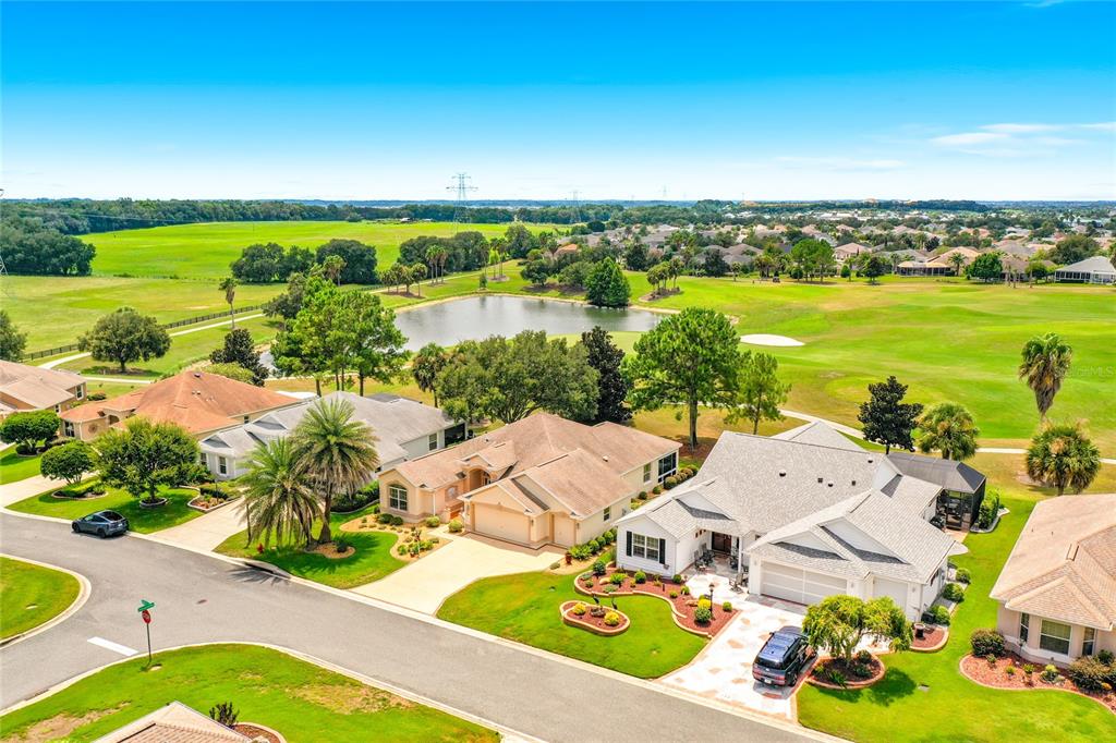An aerial view shows suburban houses with driveways and lawns bordering a golf course pond — 268 LAWTHORN STREET, THE VILLAGES, FL