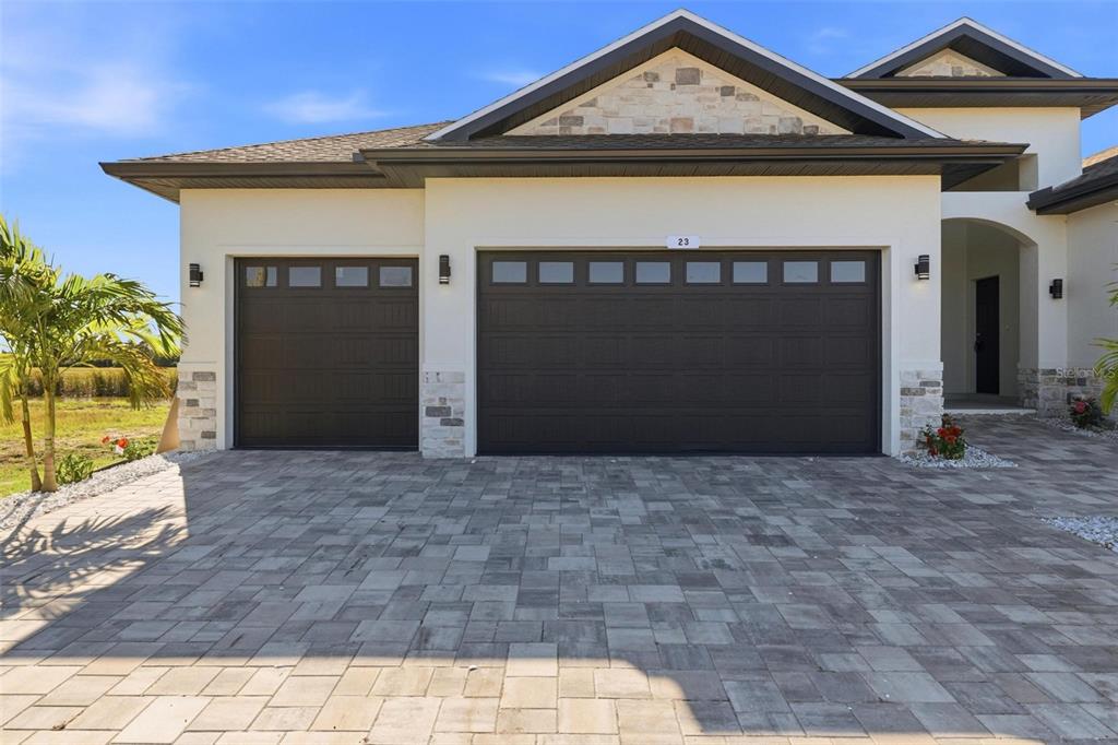 A house exterior features a three-car garage, stone accents, and a paved driveway — 23 WREN DRIVE, PLACIDA, FL