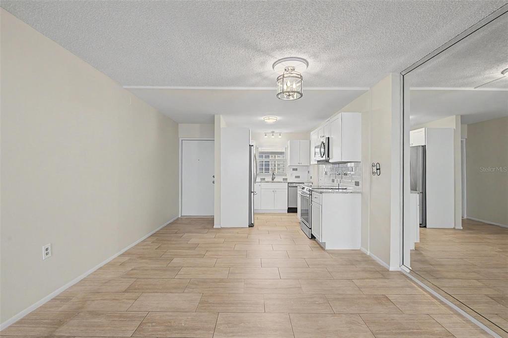 A kitchen and dining area with light-colored tile flooring, white cabinetry, and a mirrored wall — 9 FORBES PLACE UNIT 507, DUNEDIN, FL