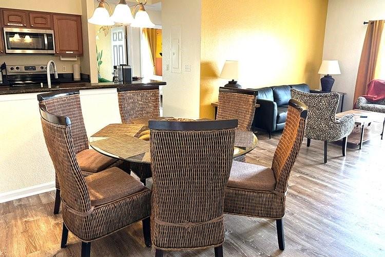 A dining area with wicker chairs sits adjacent to a kitchen and a living room — 8101 RESORT VILLAGE DRIVE UNIT 31501, ORLANDO, FL