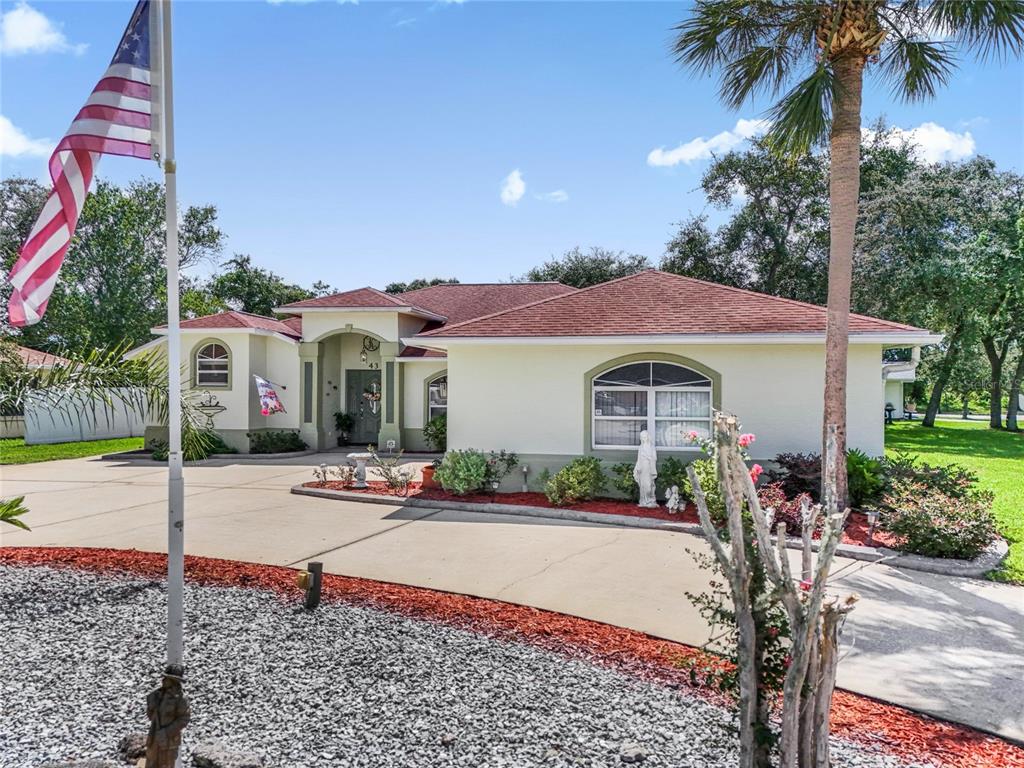 A single-story house with a red roof, stucco exterior, and a large concrete driveway — 43 FOLSON LANE, PALM COAST, FL