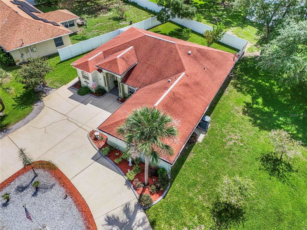 An aerial view shows a single-story house with a red roof, driveway, and fenced yard — 43 FOLSON LANE, PALM COAST, FL