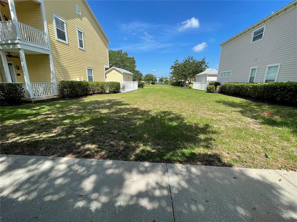 A grassy lot sits between two multi-story residential buildings under a clear blue sky — 1436 REUNION BOULEVARD, REUNION, FL