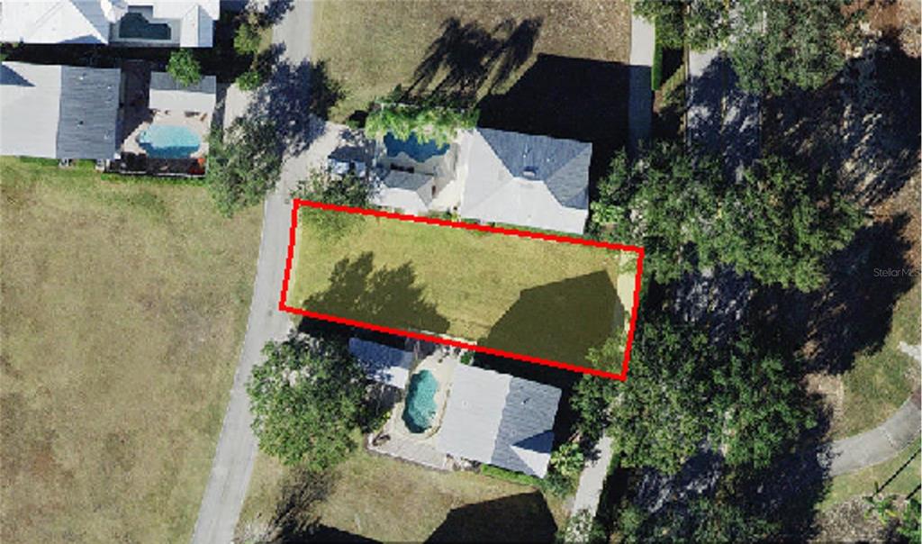 This aerial view shows a rectangular vacant lot situated between two houses with swimming pools — 1436 REUNION BOULEVARD, REUNION, FL