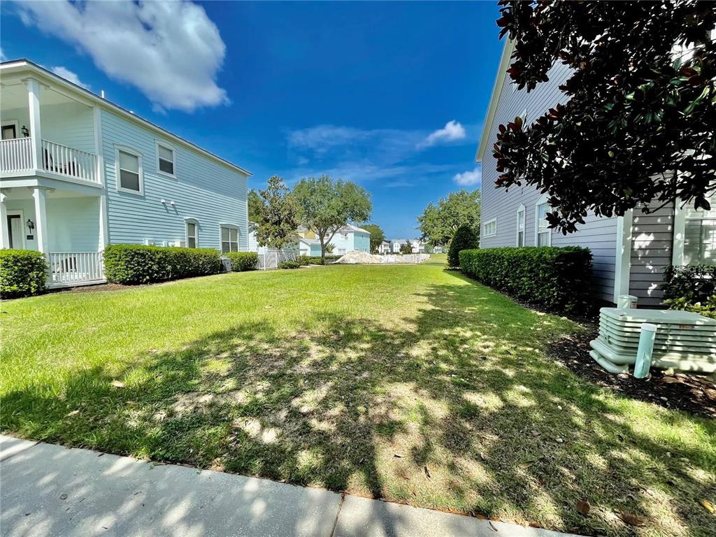 A grassy yard sits between two light-colored multi-story residential buildings under a blue sky — 1436 REUNION BOULEVARD, REUNION, FL