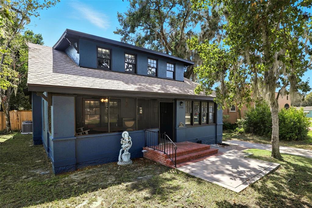 A blue two-story house features a screened front porch and a brick entrance — 1510 WASHINGTON AVENUE, EUSTIS, FL