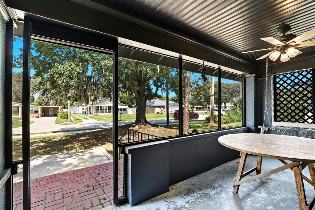 A screened-in porch with a brick floor, a wooden table, and a ceiling fan — 1510 WASHINGTON AVENUE, EUSTIS, FL