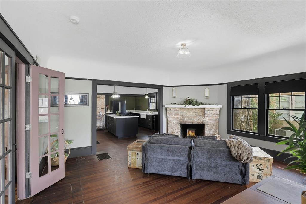 A living room with a brick fireplace, dark wood floors, and a view into a kitchen — 1510 WASHINGTON AVENUE, EUSTIS, FL