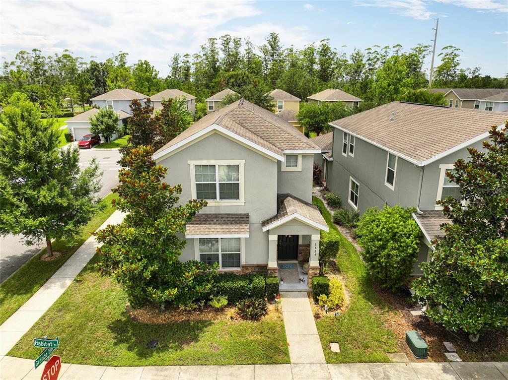 A two-story house with beige stucco siding, stone accents, and a covered front entryway — 6834 HABITAT DRIVE, HARMONY, FL