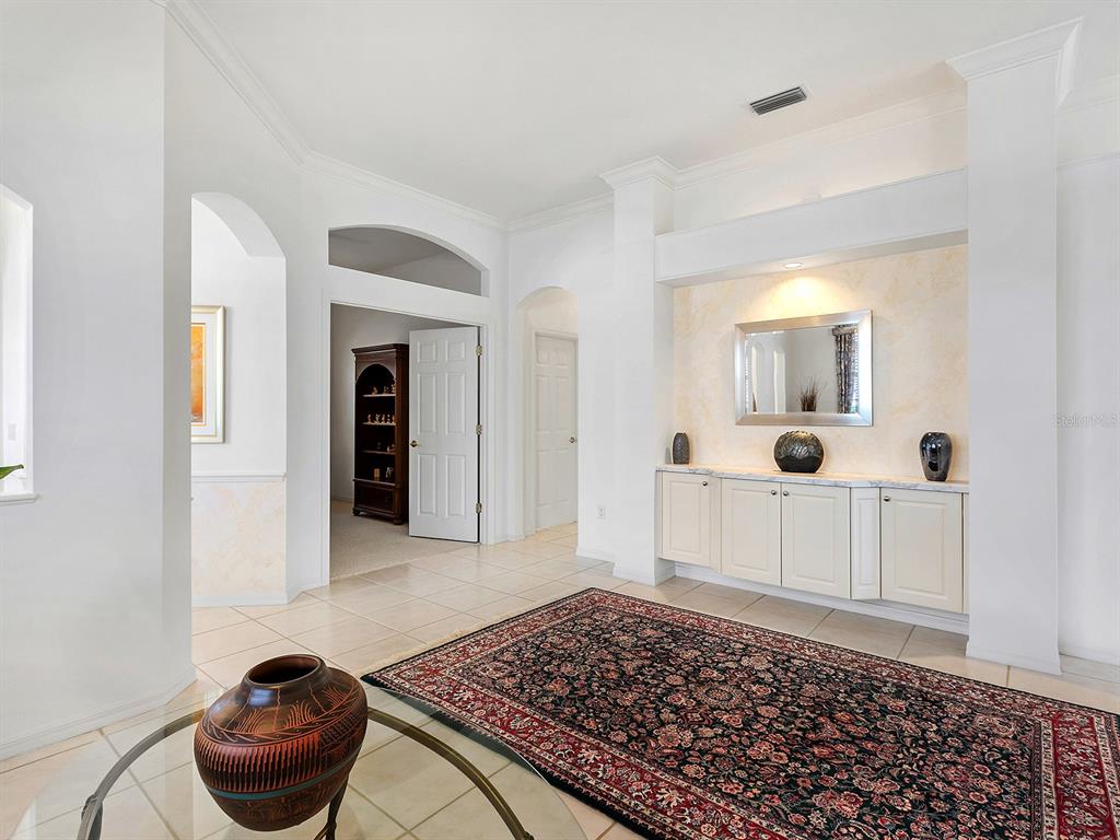 A tiled entryway features a large area rug, built-in cabinetry, and a decorative mirror — 10106 GLENMORE AVENUE, BRADENTON, FL