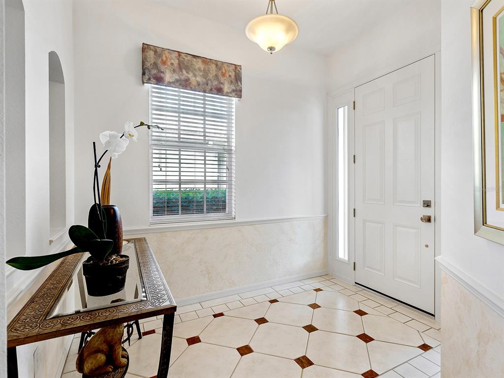 A bright entryway features tiled floors with brown accents, a console table, and a window — 10106 GLENMORE AVENUE, BRADENTON, FL