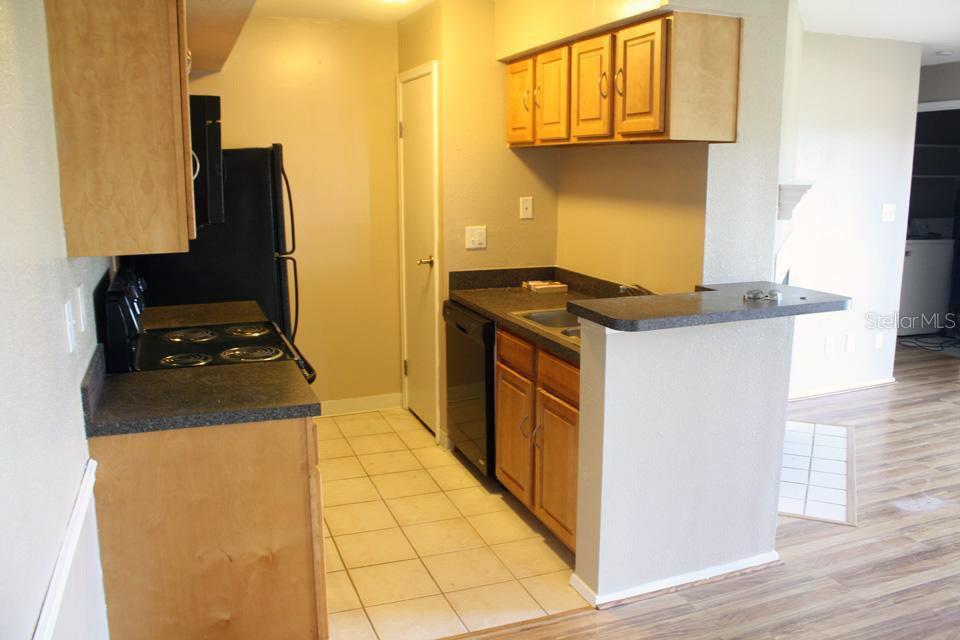 A kitchen features light wood cabinets, black appliances, dark countertops, and a tiled floor — 9100 DR MARTIN LUTHER KING JR STREET N UNIT 906, ST PETERSBURG, FL