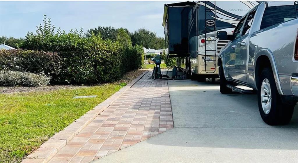 A paved walkway runs alongside a concrete driveway featuring a parked truck and an RV — 9531 SE 47TH WAY UNIT 280, WEBSTER, FL